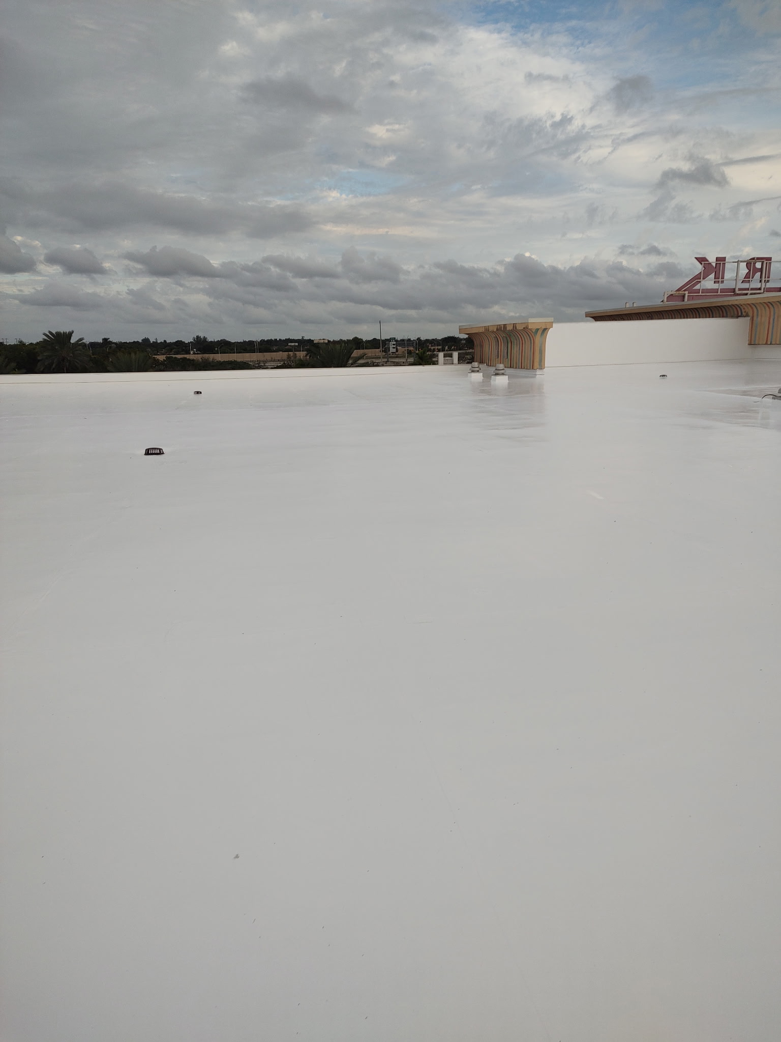 Roof coating application in progress with equipment